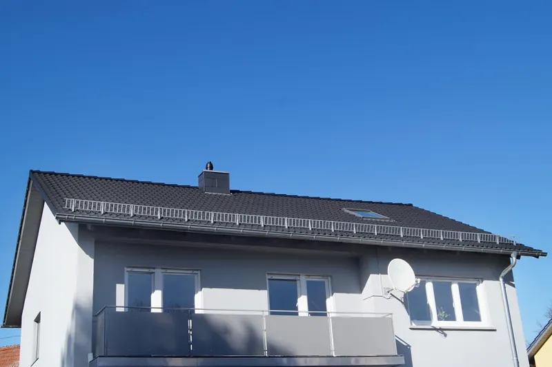 Einfamilienhaus mit anthrazitfarbenem Dach und Schneefanggitter