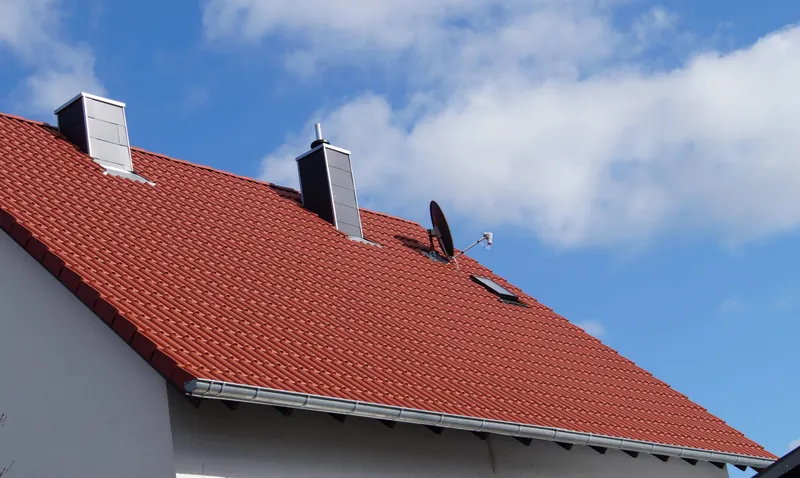 Neu eingedecktes Ziegeldach mit Kaminkopf und Satellitenschüssel