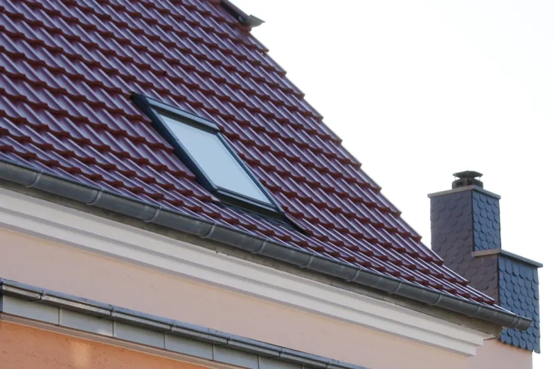 Dachfenster in einem Ziegeldach neben verkleidetem Kamin