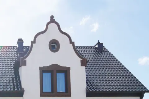 Schweifgiebel an einem Altbau mit dunklem Dach