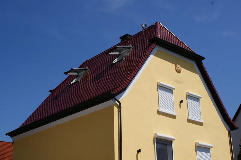 Mansarddach mit Dachfenstern auf gelbem Wohnhaus