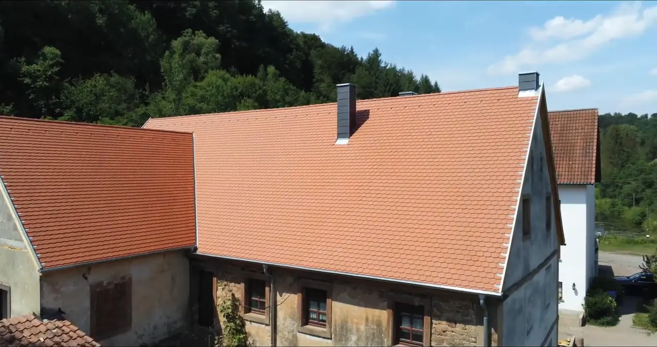 Stampermühle mit neuem Dach vor bewaldetem Hang